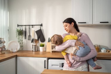 Anne modern mutfakta dururken bebeği tutuyor.