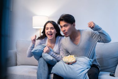 Asyalı genç çift evdeki oturma odasında film izliyor.