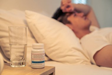 Pijamalı Asyalı hasta, yakışıklı bir erkek karanlık bir gecede yatak odasında uyuyor. Çekici genç adam ateş hastalığı ve evde yatarken öksürük yüzünden kötü hissediyor. Sağlık ve tıbbi konsept.