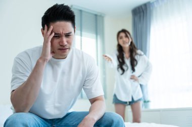 Asyalı genç çift kavga sonrası acı çekerek yatakta oturuyor..