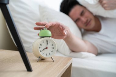 Yakışıklı erkek kendini tembel ve yorgun hisseder. Yatak odasında rahat bir yatakta uzanır. Gürültüyü duymazdan gelir ve uyanmak istemez.