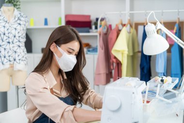 Asyalı güzel terzi kadın terzi atölyesinde giysiler üzerinde çalışıyor..