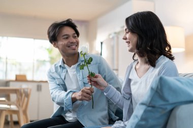 Asyalı genç adam sürpriz yaptı ve gül çiçeğini güzel kız arkadaşına verdi.