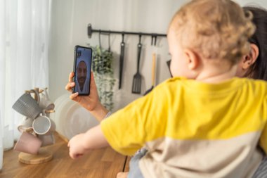 Akıllı telefondan video ararken kucağında çocuk tutan kadın
