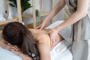 Asyalı genç bir kadın sırt masajı sırasında mutlu ve rahatlamış hissediyor.