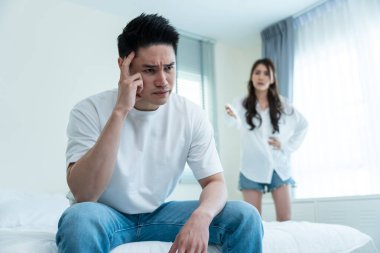 Asyalı genç çift kavga sonrası acı çekerek yatakta oturuyor..