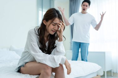 Asyalı genç çift kavga sonrası acı dolu tartışmalarla yatakta oturuyor. Yeni evli erkek ve kadın ağlıyor ve yatak odasındaki anlaşmazlıkları için üzülüyorlar. Aile sorunları ayrılığı kavramı.