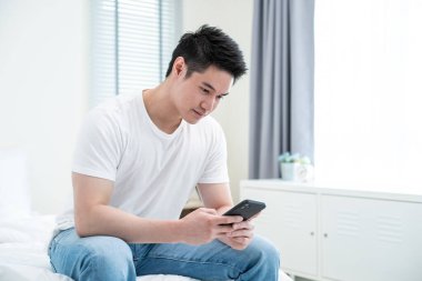 Yakışıklı Asyalı adam akıllı telefon kullanıyor.