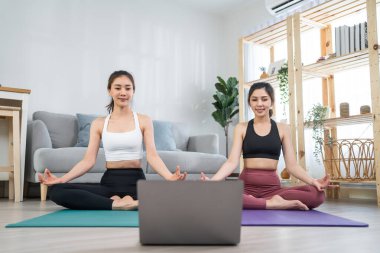Asyalı aktif kadın arkadaşlar evde birlikte Yoga pilates yapıyorlar..