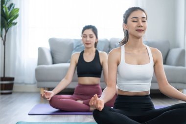 Asian active women friends doing Yoga Pilates workout together at home.