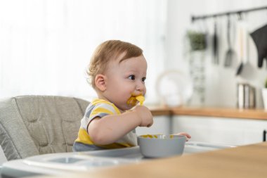 Bebek sandalyede oturup kaseden yiyor.