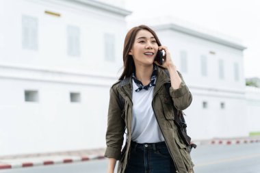 Beyaz binanın yakınında akıllı telefondan konuşan bir kadın.