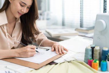 Genç bayan terzi ev ofisinde çalışıyor.