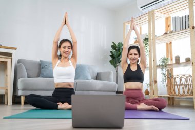 Asyalı aktif kadın arkadaşlar evde birlikte Yoga pilates yapıyorlar..