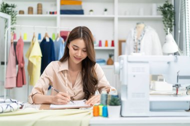 Genç bayan terzi ev ofisinde çalışıyor.