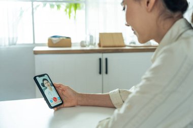 Evde otururken akıllı telefon kullanan bir kadın.