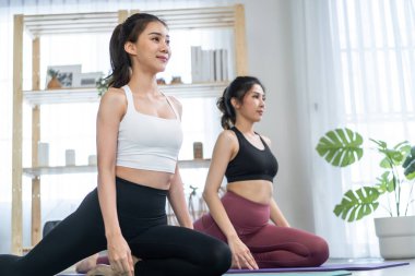 Asian active women friends doing Yoga Pilates workout together at home.