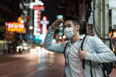 Sokakta dikilen maskeli adam selam veriyor.