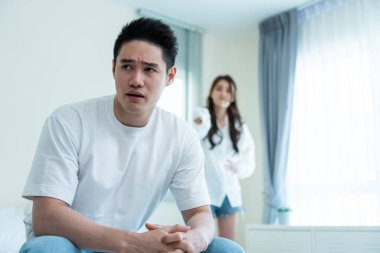 Asyalı genç çift kavga sonrası acı çekerek yatakta oturuyor..