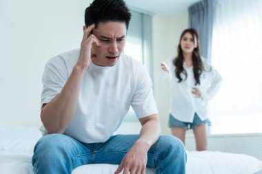 Asyalı genç çift kavga sonrası acı çekerek yatakta oturuyor..