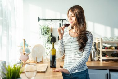 Parlak mutfakta kırmızı şaraptan hoşlanan bir kadın.