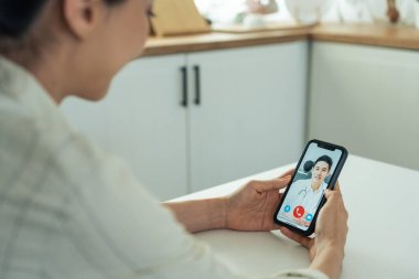 Doktorla görüntülü konuşma için akıllı telefon kullanan kadın.