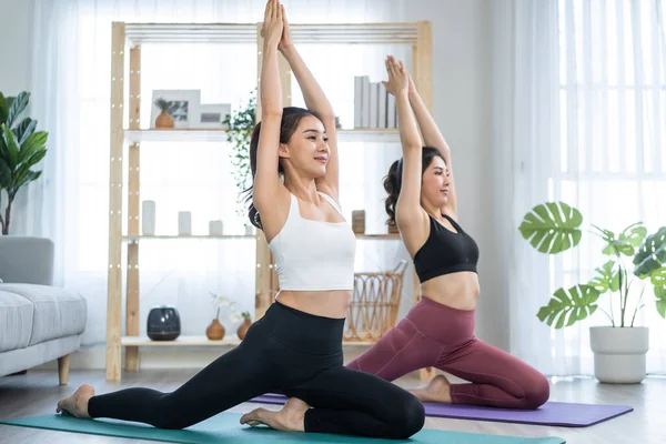 Asyalı aktif kadın arkadaşlar evde birlikte Yoga pilates yapıyorlar..