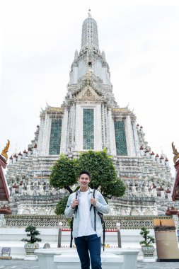 Yeşillik ve mimariyle süslü tapınağın yanında duran adam.