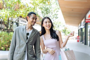 Gülümseyen çift ellerinde alışveriş torbalarıyla birlikte yürüyorlar.