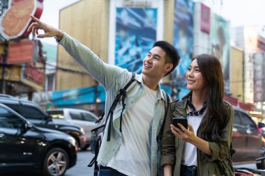 Erkek ve kadın, dışarıdaki bir şeyi işaret ederken gülümsüyor.