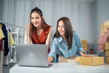 Giysi mağazasında dizüstü bilgisayarda çalışan iki kadın.