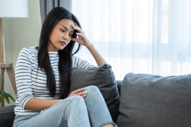 Kanepede oturan kadın düşünceli ve endişeli görünüyor.