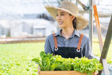Elinde taze yeşillik kutusuyla gülümseyen bir kadın.