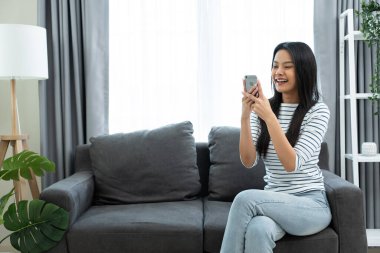 Kapalı alanda akıllı telefon kullanan gülümseyen bir kadın.