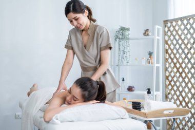 Asyalı genç kadın kendini mutlu hissediyor ve sırt masajı sırasında yağ ile rahatlıyor..