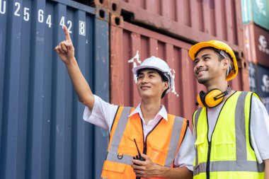 İki Asyalı işadamı konteynır limanında birlikte çalışıyor. Çekici erkek mühendis insanlar limandaki kargo nakliye gemisinin ithalat deposunda sipariş ve ürün işlemleri yapıyorlar.. 