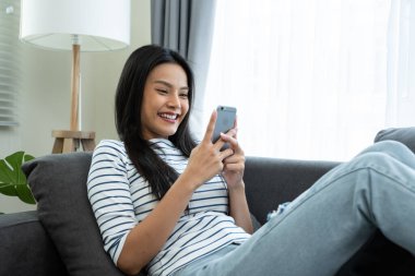 Kapalı alanda akıllı telefon kullanan gülümseyen bir kadın.