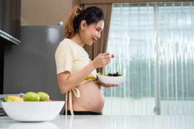 Genç Asyalı hamile kadın evdeki mutfakta.