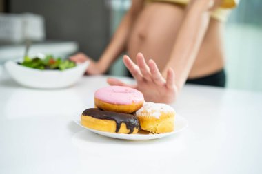 Masadaki renkli çöreklere uzanan bir kadın.