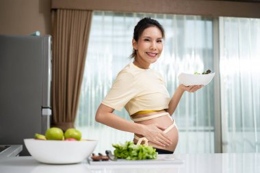 Genç Asyalı hamile kadın evdeki mutfakta.