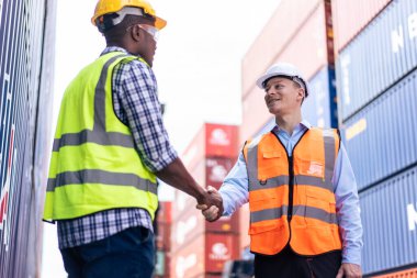 Kafkas işadamı ve konteynır limanında çalışan Afrikalı işçi. Çekici erkek, işlemler bittikten sonra kargo gemisindeki depo lojistik terminalinde el sıkışıyor..