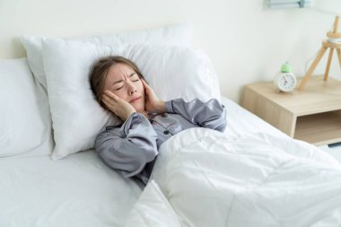 Sabahları pijamalı, hayal kırıklığına uğramış beyaz bir kız yatakta uyur. Çekici genç bir kadın gürültü yüzünden üzgün ve kızgın bir şekilde uzanıyor ve yatak odasında kulaklarına rahat bir battaniye örtüyor.