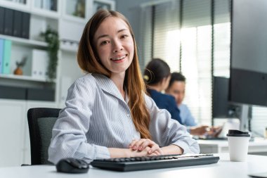 Ofiste çalışan Kafkasyalı genç iş kadınının portresi. Güzel, çekici bir çalışan kız iş yerinde masada otururken mutlu ve kendinden emin hissediyor. İş başvurusu ve işe alım kavramı