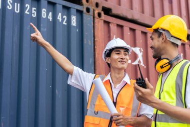 İki Asyalı işadamı konteynır limanında birlikte çalışıyor. Çekici erkek mühendis insanlar limandaki kargo nakliye gemisinin ithalat deposunda sipariş ve ürün işlemleri yapıyorlar..