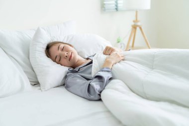 Pijamalı güzel beyaz kız sabahları uyanmak istemezmiş. Çekici genç bir kadın üzgün ve yorgun hisseder sonra da uzanıp yatak odasında yatar. Etkinlik yaşam tarzları konsepti.