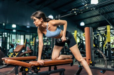 Spor salonunda kas geliştirmek için beyaz kadın spor eğitmeni. Spor kıyafetleri içinde spor salonundaki aktif, güzel formda atlet kız spor salonundaki kol ve sağlık hizmetleri için halter kaldırıyor..