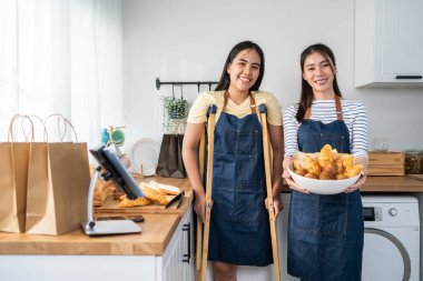 Asyalı kadın ampüte bacak portresi mutfakta arkadaşıyla duruyor. Çekici bacaksız kadın evde fırın pişiriyor. Hafta sonu aktivitesi için oda arkadaşıyla birlikte. Sonra da kameraya bakıyor..