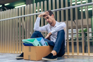 Beyaz iş adamı şirketteki işsizlikten sonra dışarıda oturuyor. Çekici bir erkek işçi, dünya ekonomik sorunu ve zorluğu yüzünden işini kaybettikten sonra üzgün ve üzgün hissediyor.