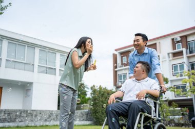 Asyalı çekici bir aile, Down Sendromu 'nun oğluyla bahçede oynuyor. Güzel bir çift, baba ve anne desteği dikkat edin. Otizmli ya da özel ihtiyaçları olan genç adam arka bahçede, evde.