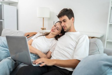 Beyaz bir çift evdeki oturma odasında dizüstü bilgisayar kullanıyor. Çekici, romantik, yeni evli bir erkek ve kadın yerde oturuyorlar. Boş vakitlerini internette, internet haberlerinde birlikte geçiriyorlar.